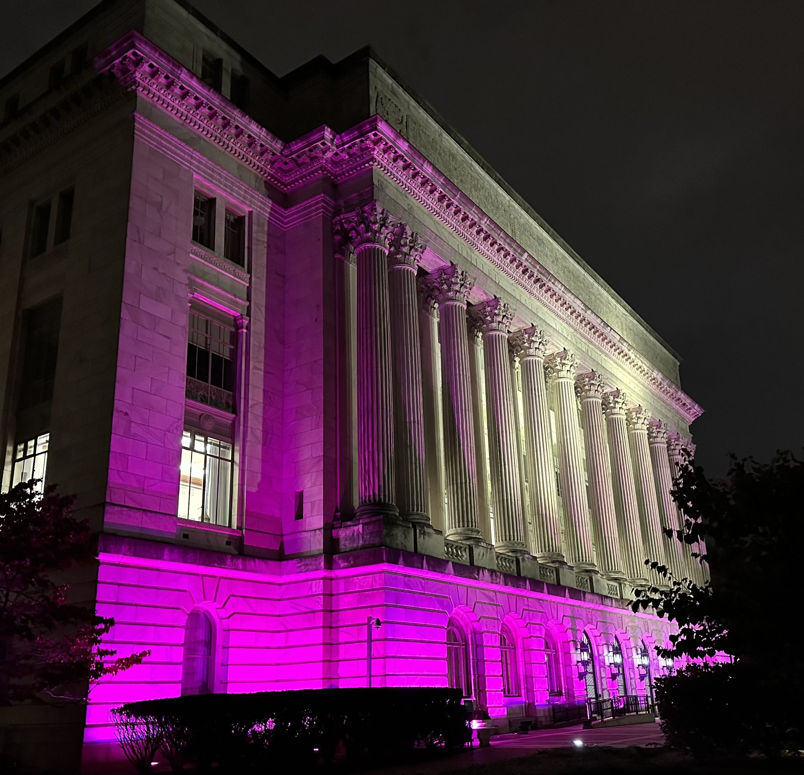 Large building showing outdoor pink lighting lit up at night from left side