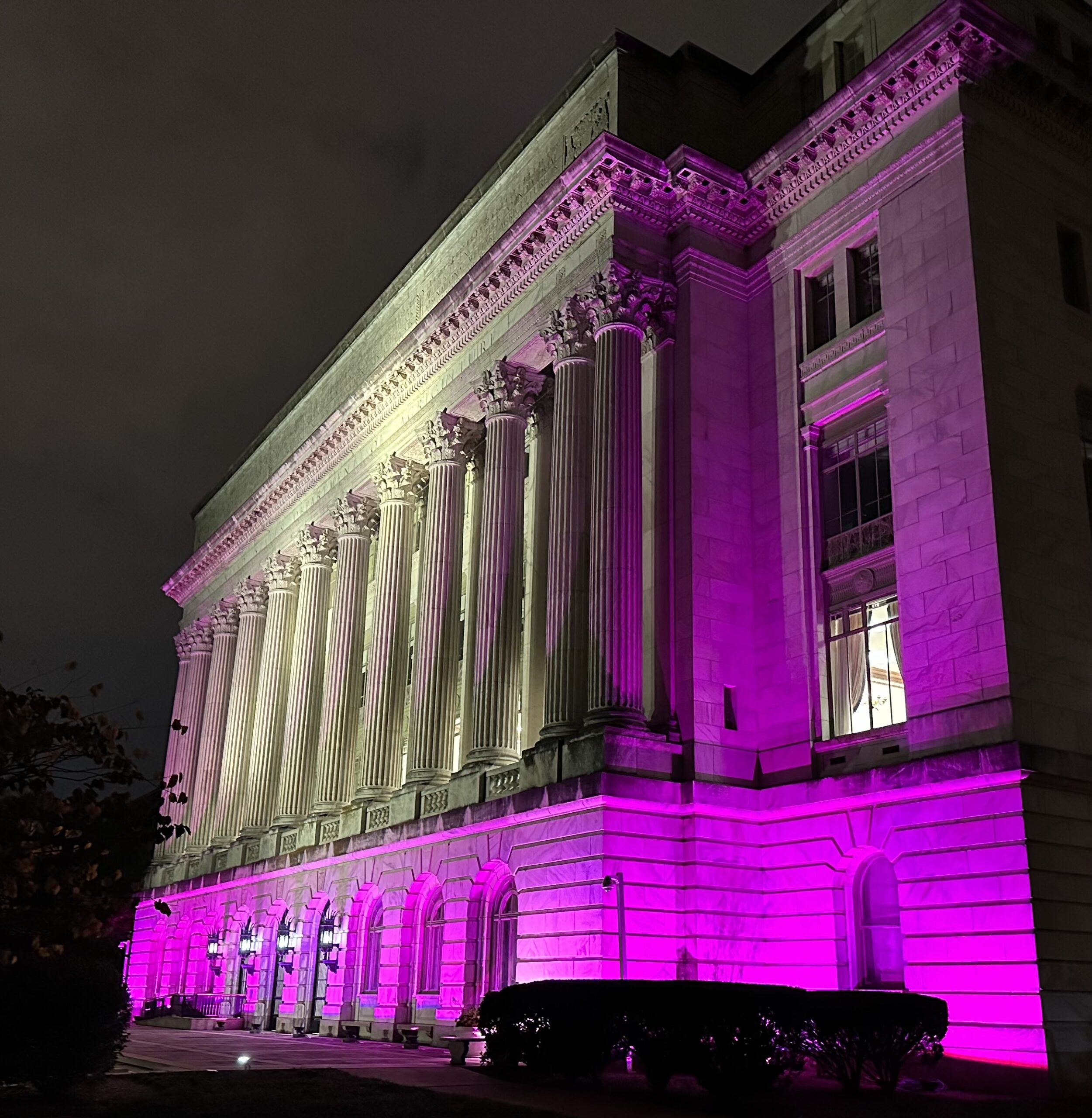 Large building showing outdoor pink lighting lit up at night from right side