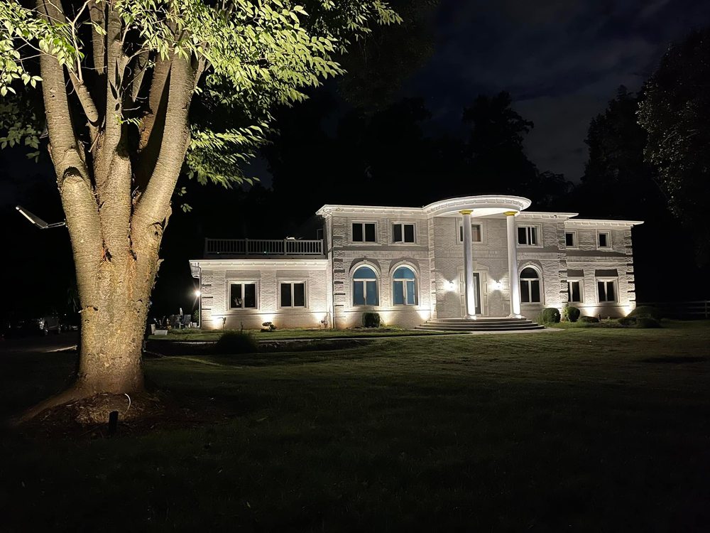 Front view with lit tree of illuminated estate at night